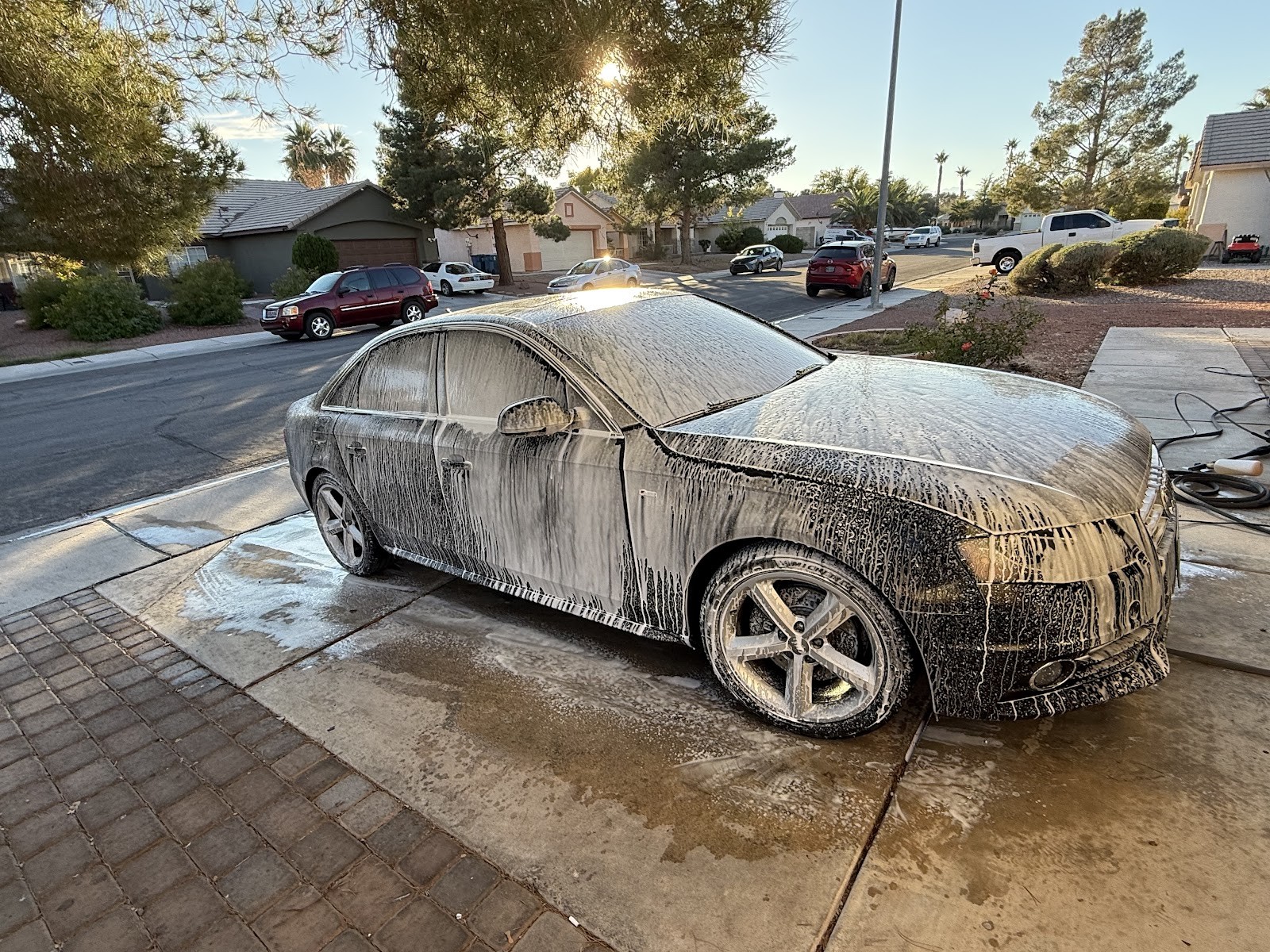 Audi sedan covered in foam soap during a wash on a driveway