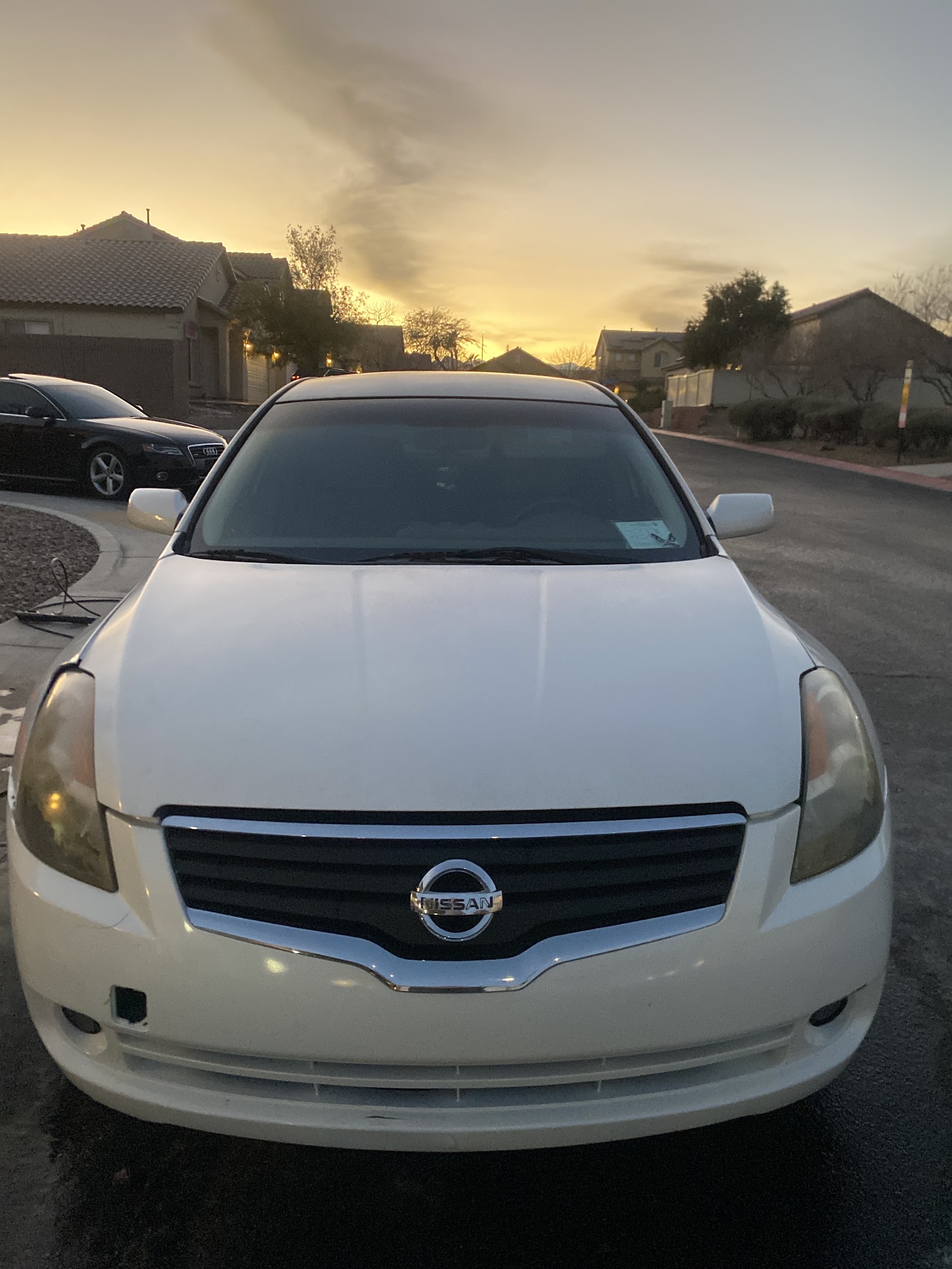 White Nissan Altima detailed at sunset in a residential driveway