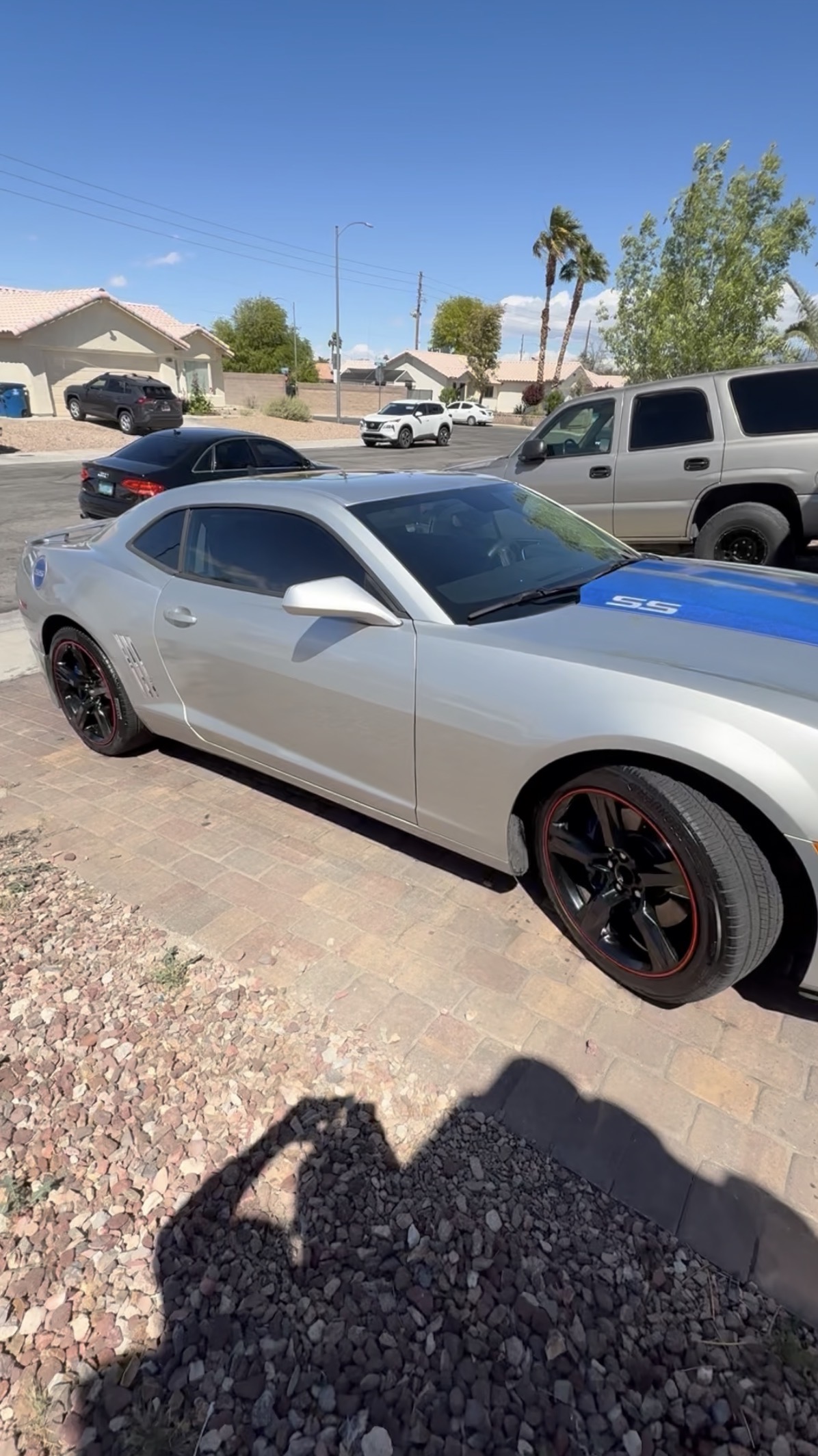 Silver Chevrolet Camaro SS with a blue racing stripe in a driveway